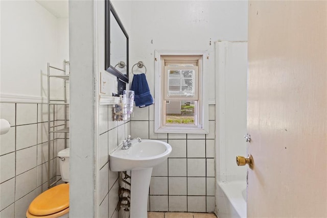 305 N Reimer, Corn, OK 73024 - bathroom featuring tile walls, toilet, a tub to relax in, a sink, and wainscoting
