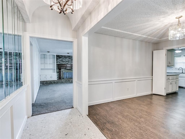 3605 Country Clb, Moore, OK 73160 - foyer with a chandelier, a decorative wall, a wainscoted wall, a fireplace, and a textured ceiling