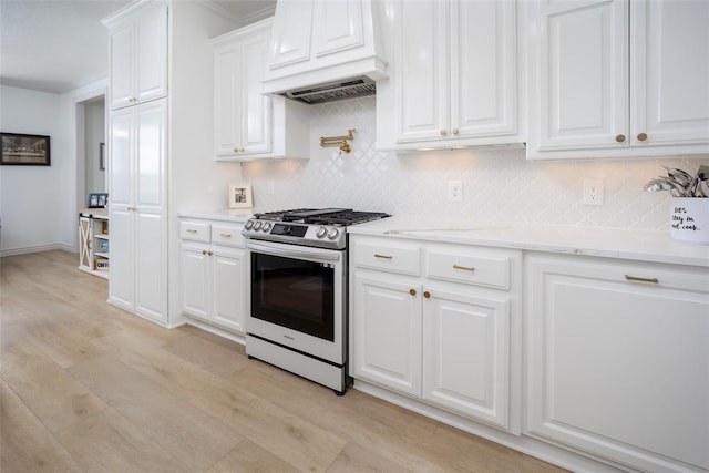 271 Taylam Rd, Goldsby, OK 73093 - kitchen featuring stainless steel range with gas stovetop, custom range hood, light wood-type flooring, decorative backsplash, and white cabinetry