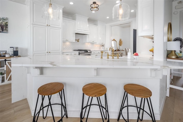 271 Taylam Rd, Goldsby, OK 73093 - kitchen featuring stainless steel range with gas stovetop, white cabinetry, a peninsula, a breakfast bar, and recessed lighting