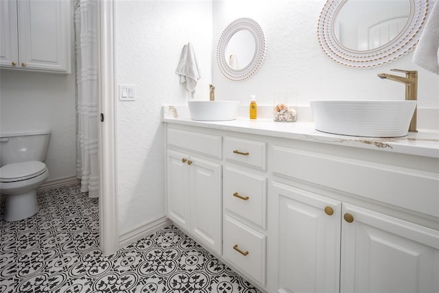 271 Taylam Rd, Goldsby, OK 73093 - full bathroom with double vanity, toilet, baseboards, and a textured wall