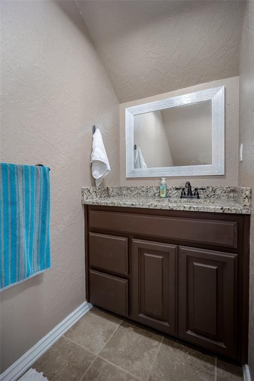 271 Taylam Rd, Goldsby, OK 73093 - bathroom featuring a textured wall, vanity, lofted ceiling, and baseboards