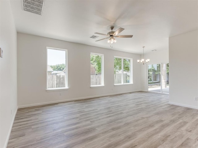 empty room featuring a chandelier, baseboards, a ceiling fan, and light wood finished floors