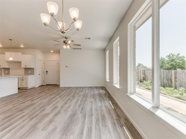 unfurnished living room with light wood-type flooring, baseboards, ceiling fan, a chandelier, and recessed lighting