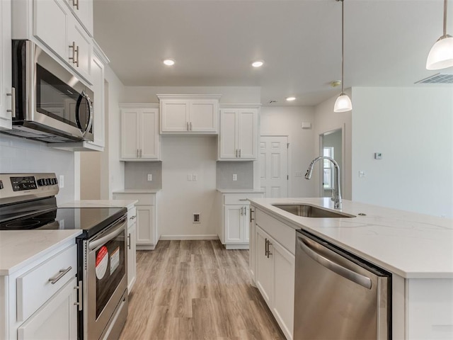 kitchen with stainless steel appliances, a sink, an island with sink, light wood-type flooring, and white cabinetry