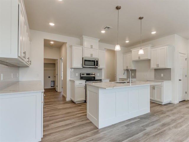 kitchen featuring appliances with stainless steel finishes, a sink, light wood-type flooring, backsplash, and recessed lighting
