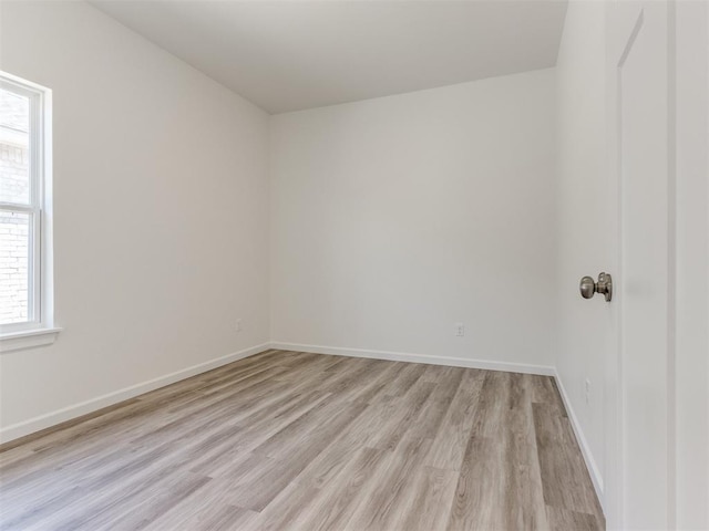 spare room featuring light wood-type flooring and baseboards