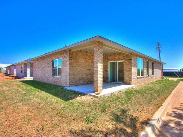 rear view of property with brick siding, a patio area, and a yard