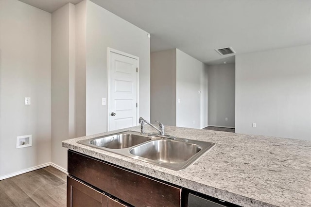 11700 NW 95th St, Yukon, OK 73099 - kitchen featuring a sink, light countertops, dark wood-style flooring, dark brown cabinetry, and baseboards