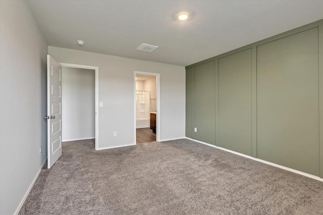 11700 NW 95th St, Yukon, OK 73099 - unfurnished bedroom featuring dark colored carpet, baseboards, ensuite bath, and multiple closets