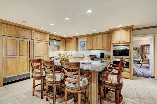 1114 Sherwood Ln Unit B-2, Nichols Hills, OK 73116 - kitchen featuring double oven, wall chimney range hood, dark stone counters, recessed lighting, and light tile patterned floors