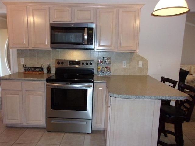 1926 E Aspen Pl, Shawnee, OK 74804 - kitchen with appliances with stainless steel finishes, a peninsula, a kitchen bar, and tasteful backsplash