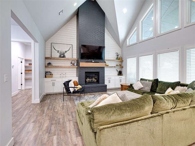 1614 S 1st Ave, Stroud, OK 74079 - living area featuring high vaulted ceiling, a brick fireplace, light wood-type flooring, and baseboards