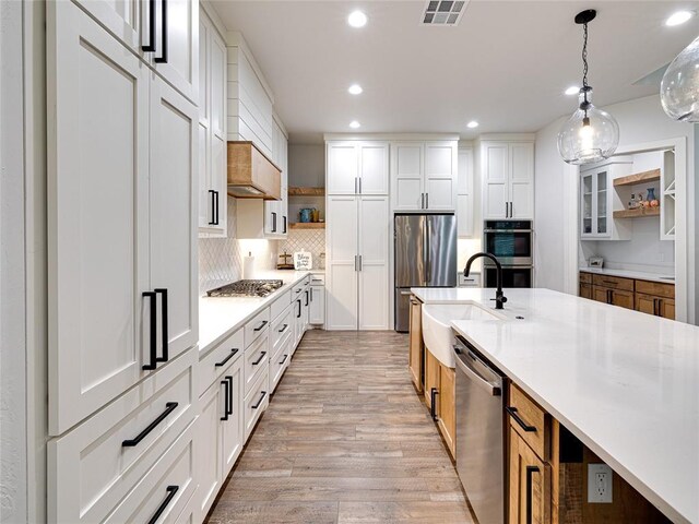 1614 S 1st Ave, Stroud, OK 74079 - kitchen with open shelves, stainless steel appliances, a sink, light wood-type flooring, and light countertops