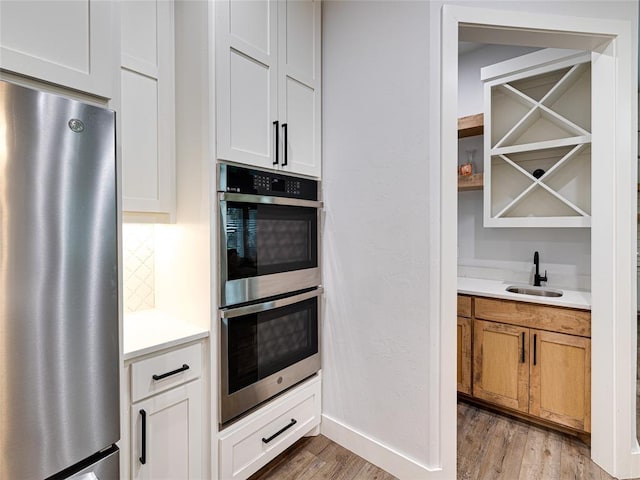 1614 S 1st Ave, Stroud, OK 74079 - kitchen with appliances with stainless steel finishes, a sink, light wood-style floors, light countertops, and baseboards