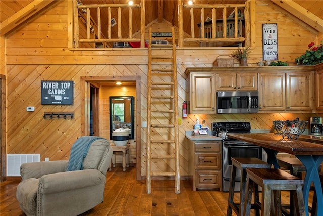 962 Red Fox Rd, Broken Bow, OK 74728 - kitchen with appliances with stainless steel finishes, wood walls, dark wood-style flooring, wood ceiling, and open floor plan