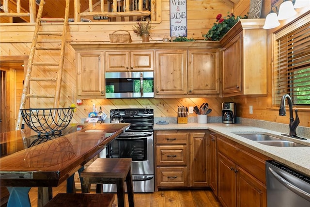 962 Red Fox Rd, Broken Bow, OK 74728 - kitchen with stainless steel appliances, a sink, wood walls, dark wood-type flooring, and light stone counters