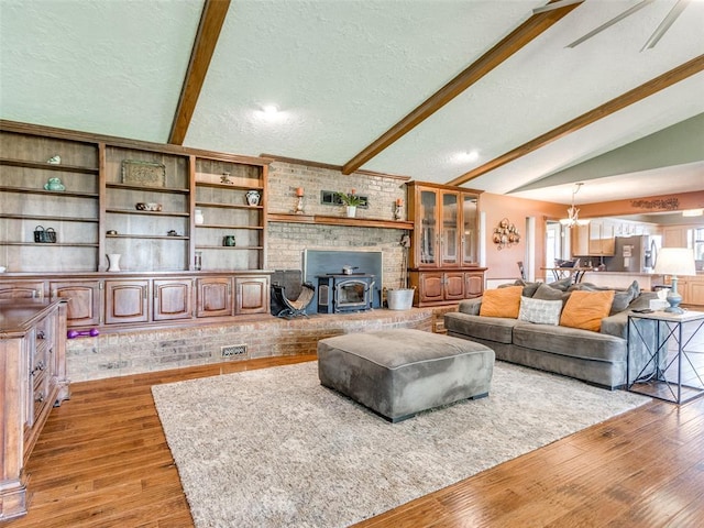13776 E Stella Rd, Newalla, OK 74857 - living room with light wood finished floors, a wood stove, a textured ceiling, and a chandelier