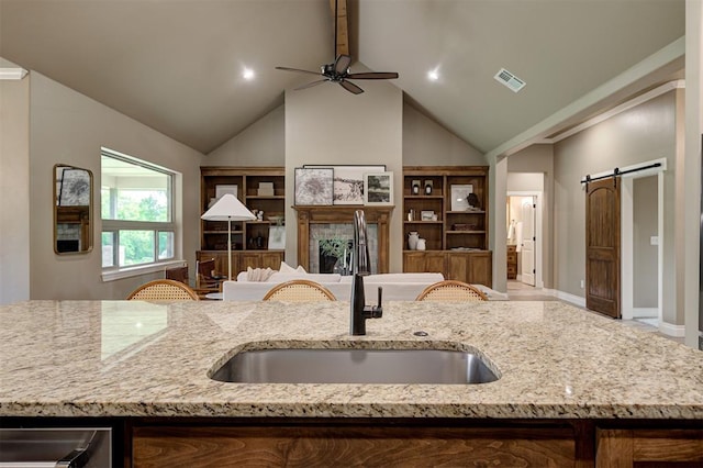 12535 Memory Ln, Edmond, OK 73025 - kitchen featuring a sink, open floor plan, a ceiling fan, light stone counters, and a barn door