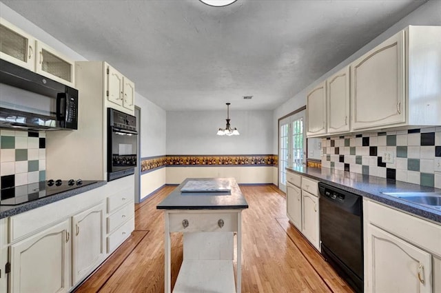 15001 Garr Pl, Oklahoma City, OK 73165 - kitchen featuring black appliances, dark countertops, light wood finished floors, and decorative backsplash