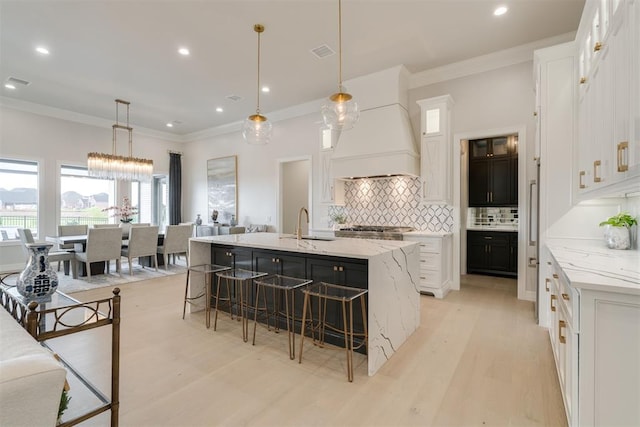 15012 Annecy Blvd, Oklahoma City, OK 73142 - kitchen with tasteful backsplash, light wood-style floors, white cabinets, custom exhaust hood, and a breakfast bar