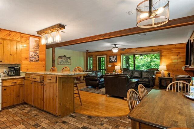 868 Red Fox Rd, Broken Bow, OK 74728 - kitchen with wooden walls, a kitchen bar, brick patterned flooring, light countertops, and open floor plan