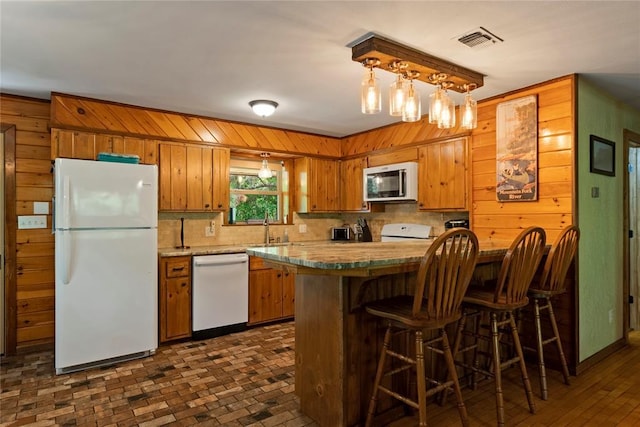 868 Red Fox Rd, Broken Bow, OK 74728 - kitchen featuring white appliances, brown cabinets, tasteful backsplash, wooden walls, and a sink