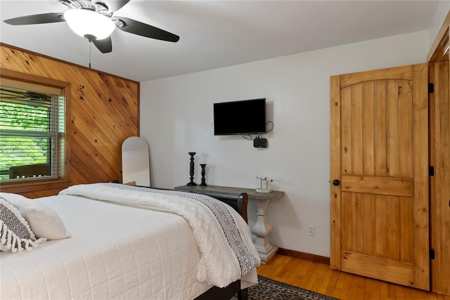868 Red Fox Rd, Broken Bow, OK 74728 - bedroom with light wood-style flooring, baseboards, wooden walls, and ceiling fan