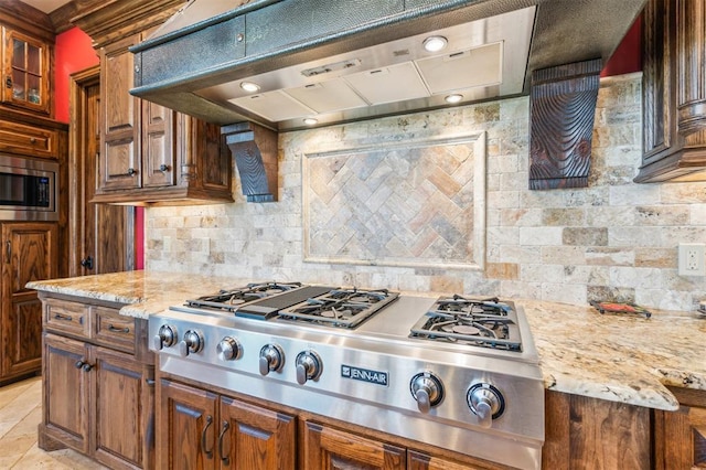 13600 W Britton Rd, Yukon, OK 73099 - kitchen featuring stainless steel appliances, under cabinet range hood, decorative backsplash, light stone countertops, and glass insert cabinets