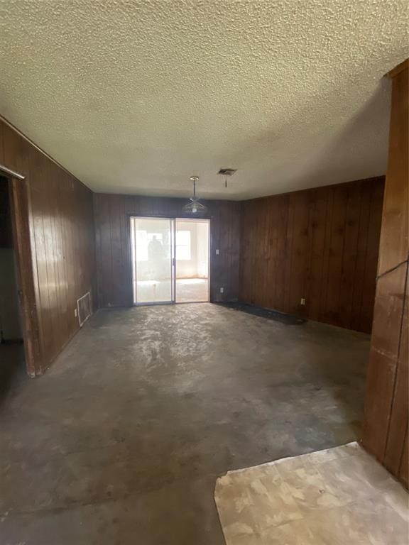 20403 E County Road 1567, Altus, OK 73521 - unfurnished dining area featuring wood walls, concrete floors, and a textured ceiling