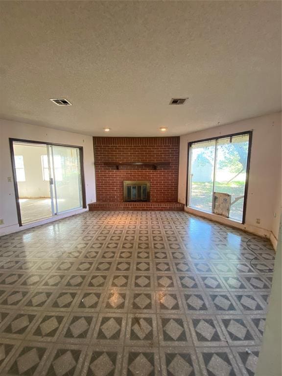 20403 E County Road 1567, Altus, OK 73521 - unfurnished living room with tile patterned floors, a textured ceiling, a fireplace, baseboards, and brick wall
