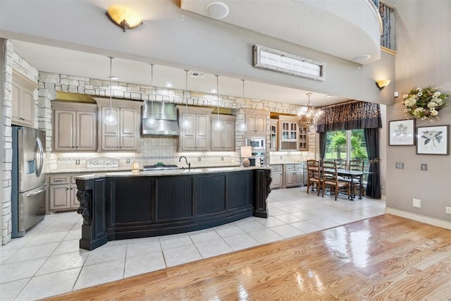 20180 Elm St, Harrah, OK 73045 - kitchen with wall chimney range hood, appliances with stainless steel finishes, a chandelier, decorative backsplash, and light tile patterned flooring