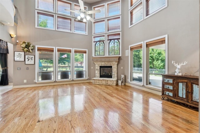 20180 Elm St, Harrah, OK 73045 - unfurnished living room featuring a ceiling fan, a high ceiling, a stone fireplace, baseboards, and wood finished floors