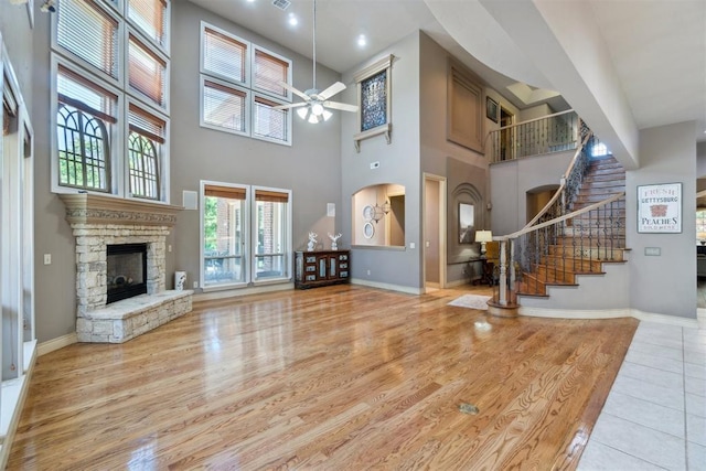 20180 Elm St, Harrah, OK 73045 - unfurnished living room with a ceiling fan, a towering ceiling, a stone fireplace, stairway, and baseboards