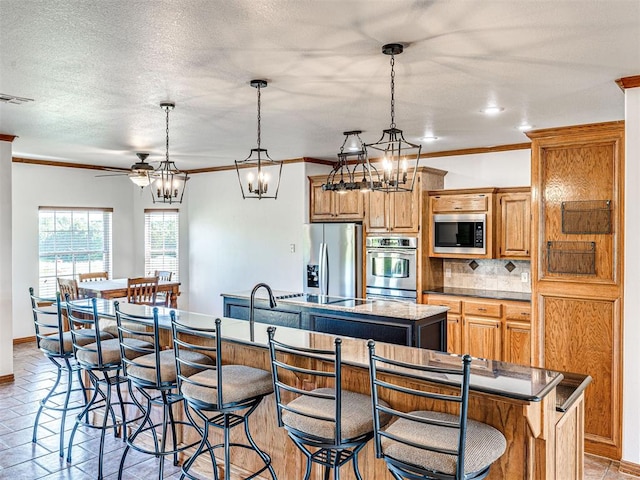 349412 E 840th Rd, Stroud, OK 74079 - kitchen with appliances with stainless steel finishes, an island with sink, backsplash, ornamental molding, and a breakfast bar area