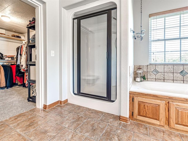 349412 E 840th Rd, Stroud, OK 74079 - bathroom featuring a stall shower, a bath, a spacious closet, baseboards, and a textured ceiling