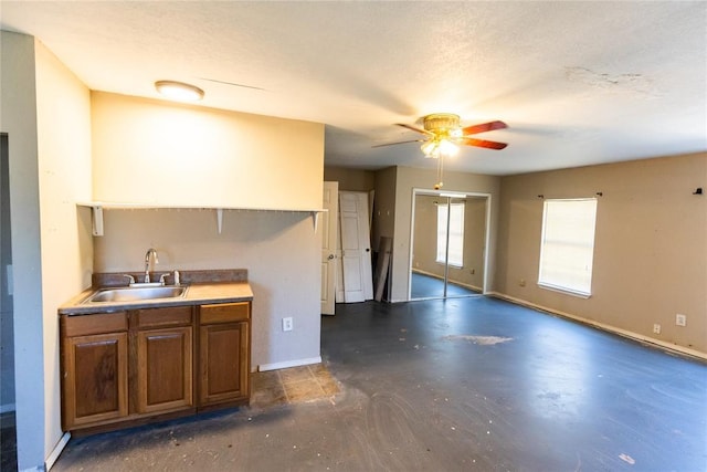 4620 SE 139th St, Oklahoma City, OK 73165 - kitchen featuring a sink, concrete floors, ceiling fan, baseboards, and brown cabinetry