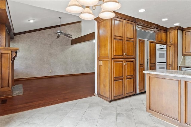5839 Hefner Village Ct, Oklahoma City, OK 73162 - kitchen with paneled built in refrigerator, a ceiling fan, double oven, crown molding, and brown cabinetry