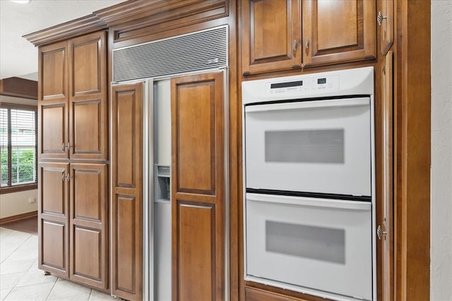 5839 Hefner Village Ct, Oklahoma City, OK 73162 - kitchen with paneled built in fridge, white double oven, brown cabinets, and light tile patterned flooring