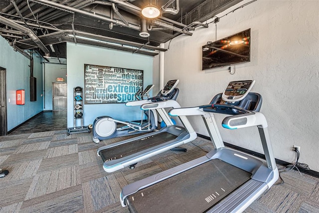 gym featuring a textured wall, carpet floors, and baseboards