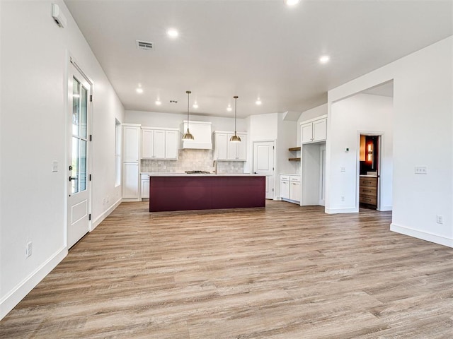 29612 Memory Ln, Norman, OK 73072 - kitchen featuring white cabinetry, premium range hood, light wood-style floors, tasteful backsplash, and a spacious island