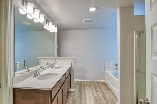 20101 Park Ln, Harrah, OK 73045 - full bathroom featuring wood finished floors, a garden tub, baseboards, double vanity, and a shower with door