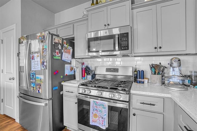 1537 Avalon Dr, Altus, OK 73521 - kitchen featuring stainless steel appliances, decorative backsplash, light stone counters, and light wood-style floors