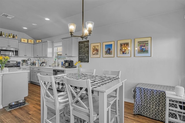 1537 Avalon Dr, Altus, OK 73521 - kitchen with stainless steel appliances, vaulted ceiling, dark wood-style flooring, light countertops, and a chandelier