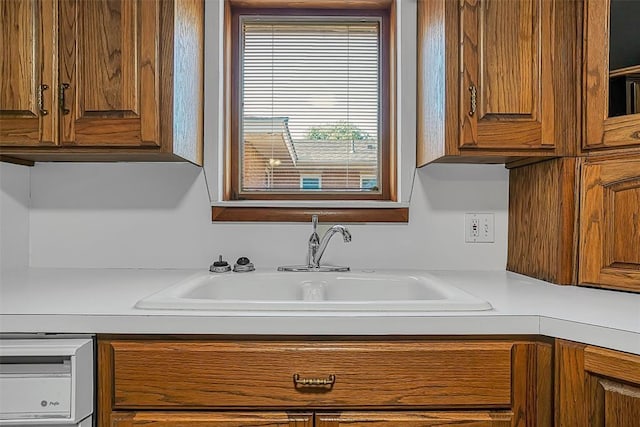 kitchen featuring a sink, brown cabinets, and light countertops