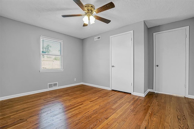unfurnished bedroom with wood finished floors, baseboards, a textured ceiling, and ceiling fan