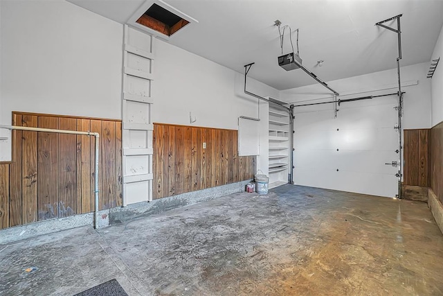 garage featuring wooden walls, a garage door opener, and wainscoting