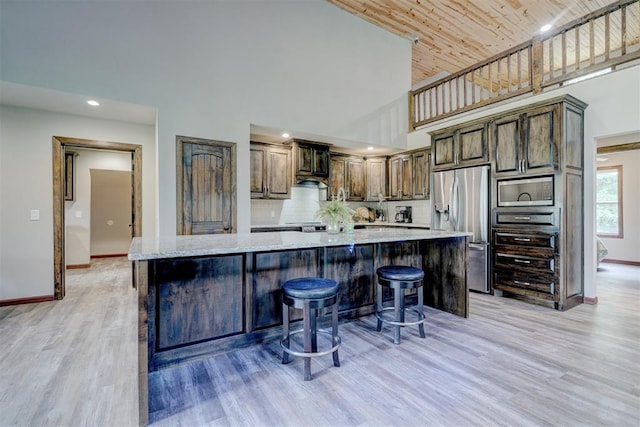 4575 Hidden Path, Kingston, OK 73439 - kitchen with stainless steel appliances, high vaulted ceiling, baseboards, light wood-style floors, and a kitchen bar