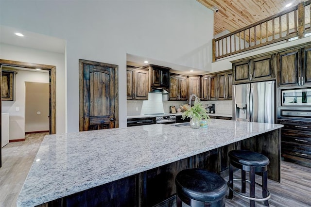 4575 Hidden Path, Kingston, OK 73439 - kitchen featuring appliances with stainless steel finishes, light wood-style floors, high vaulted ceiling, light stone counters, and backsplash