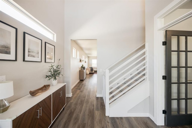 foyer entrance with dark wood finished floors, stairway, baseboards, and a towering ceiling